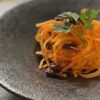 黒い器にオレンジ色のにんじんが映えるサラダ。にんじんのラペ風サラダ。