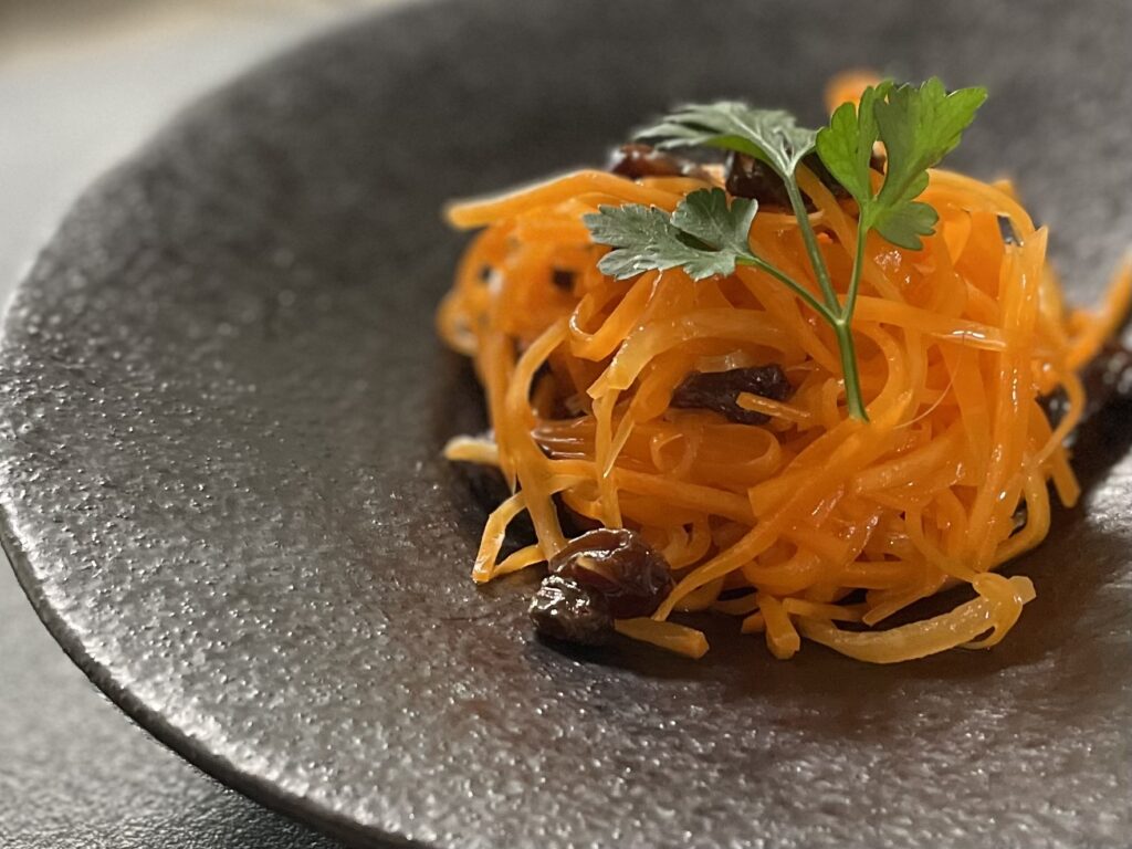 黒い器にオレンジ色のにんじんが映えるサラダ。にんじんのラペ風サラダ。