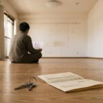 退去後の空き部屋で床に座り、退去費用の請求書を読む人の後ろ姿。手前の床には鍵と書類が置かれている