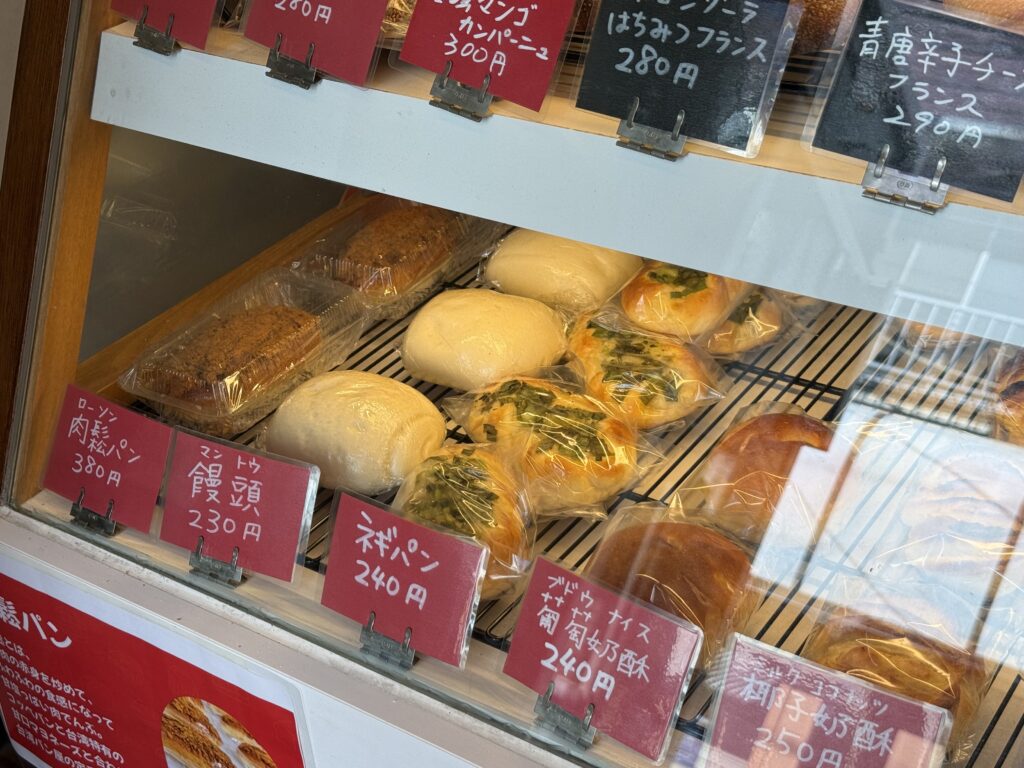 肉鬆パン、饅頭、ネギパンの赤い札が並ぶ阿美パンのショーケース