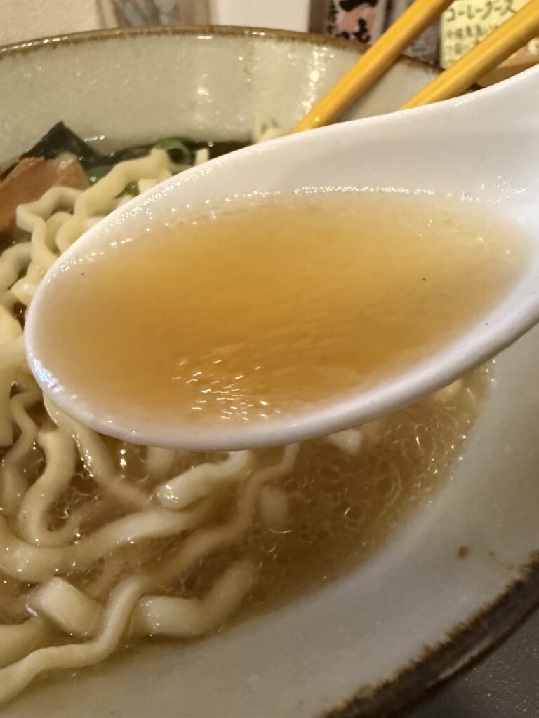レンゲですくった、澄んだ黄金色のスープ