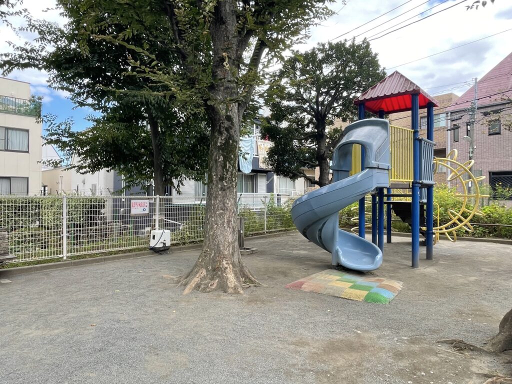 大きな木と、らせん滑り台付きの複合遊具