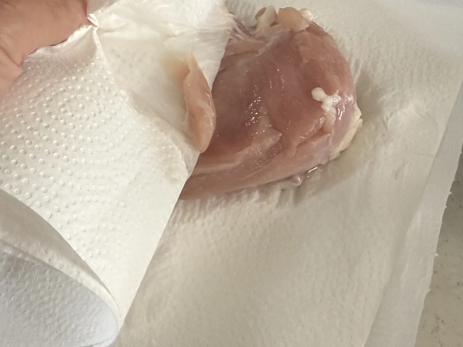 漬けた鶏むね肉の表面をキッチンペーパーで拭くところ