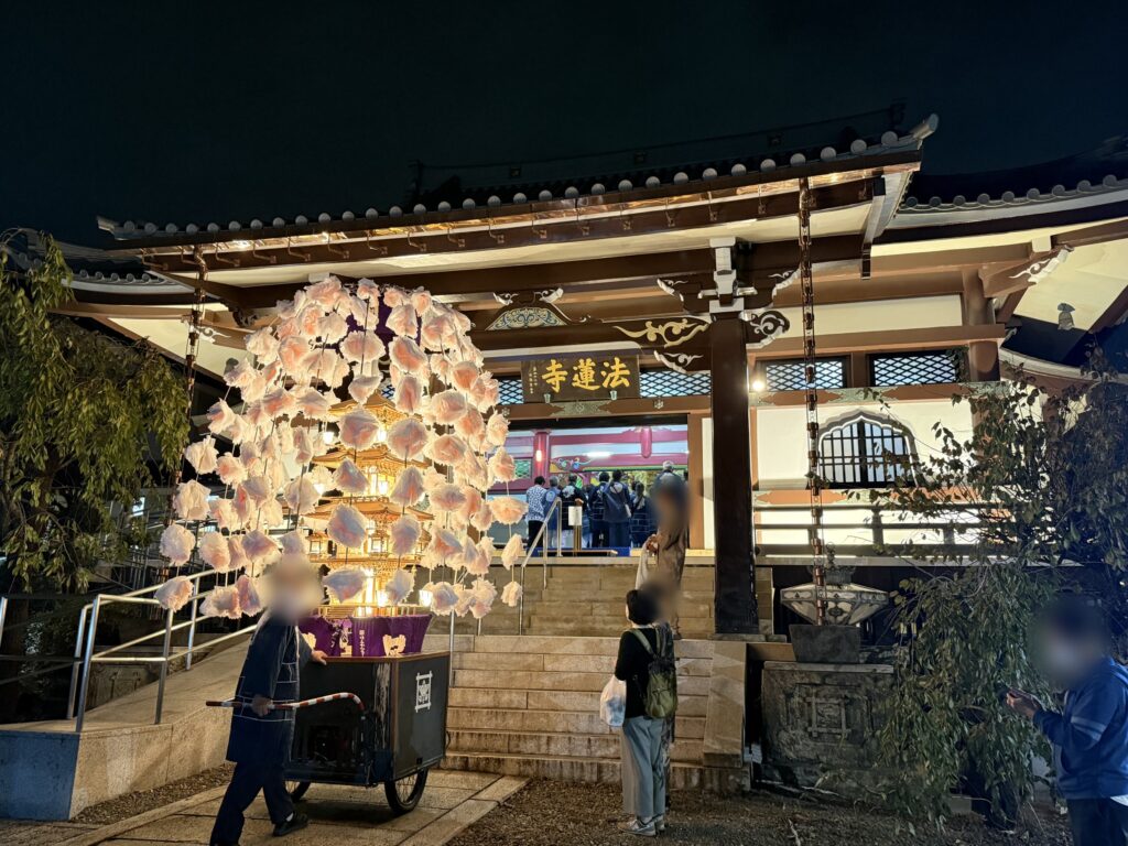 「法蓮寺」の額がかかるライトアップされた本堂と、その前に寄せられた万灯