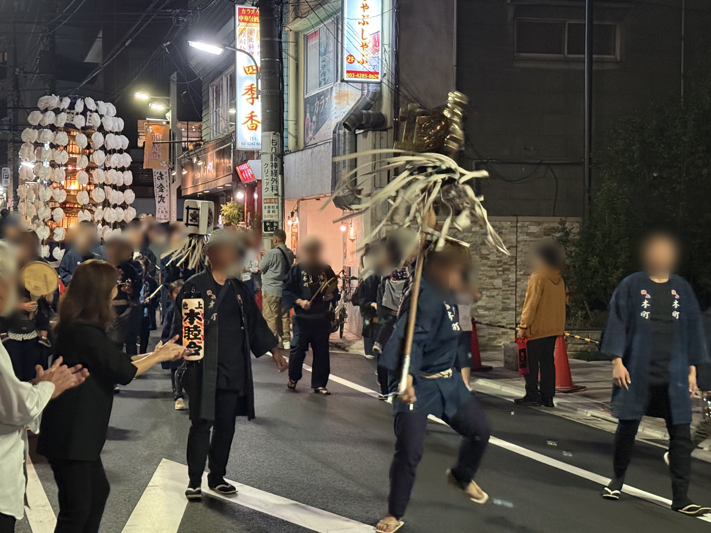 荏原町の通りで纏を振る講中と、その後ろを進む白い万灯
