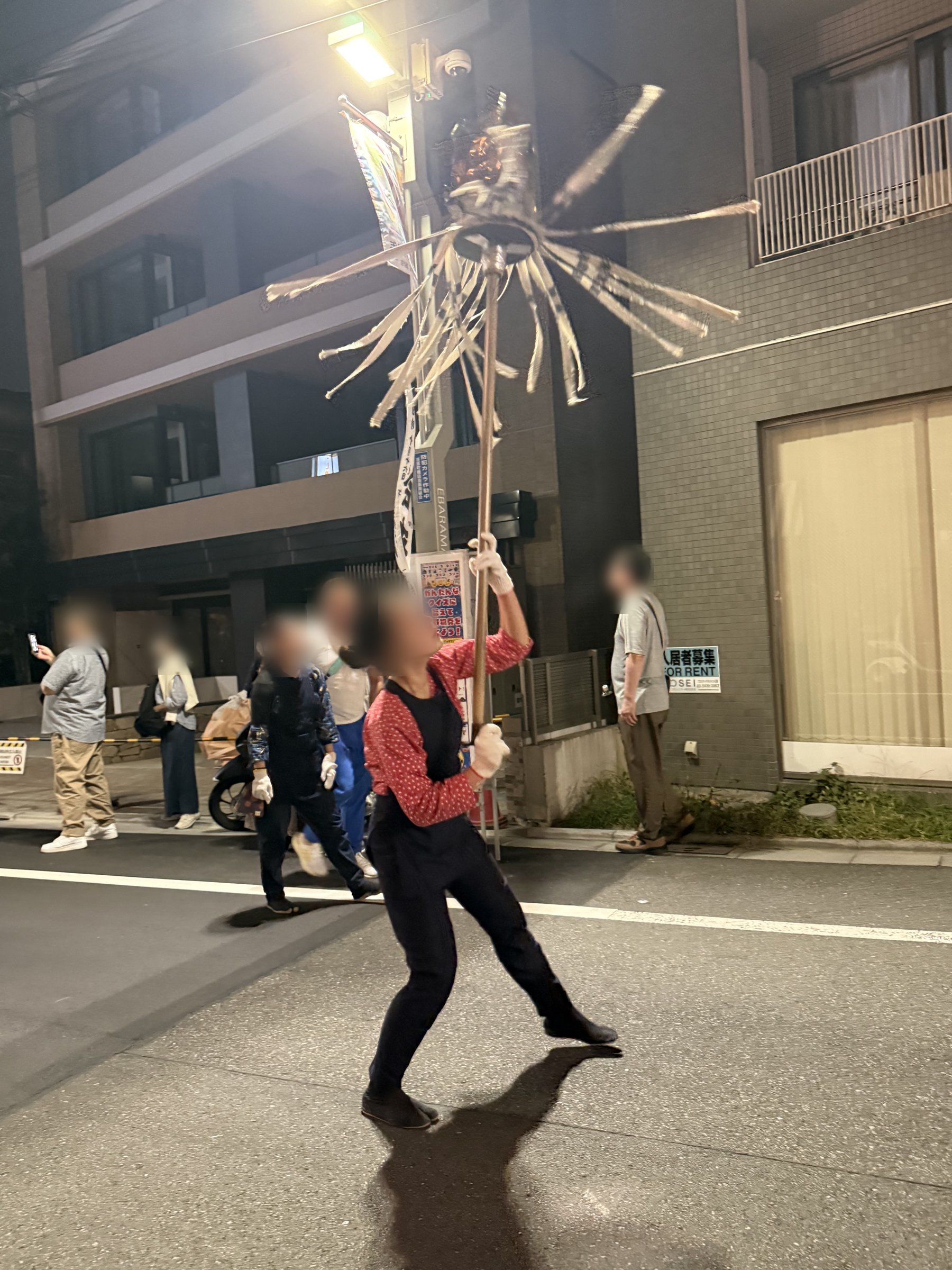 夜の通りで纏を高く掲げて振る若い女性の振り手