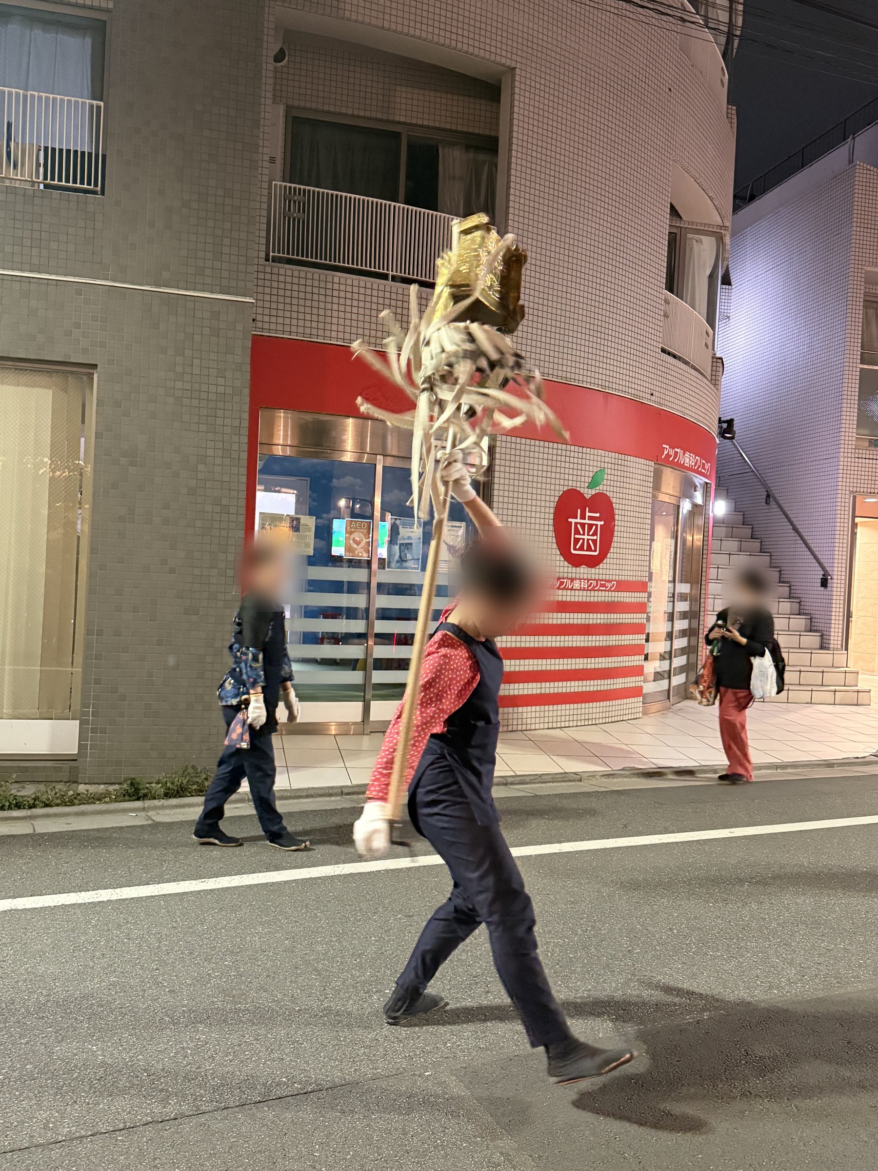 纏を片手で掲げ、足を踏み出しながら進む振り手